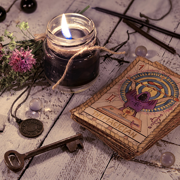 Black candle and old tarot cards on wooden planks. Halloween and fortune telling concept. Mystic background with occult and magic objects on witch table.